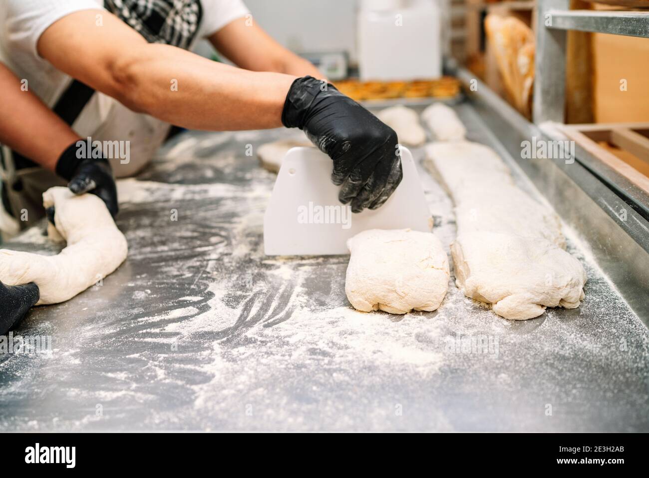 selective focus of two Latin bakers kneading and cutting the dough to