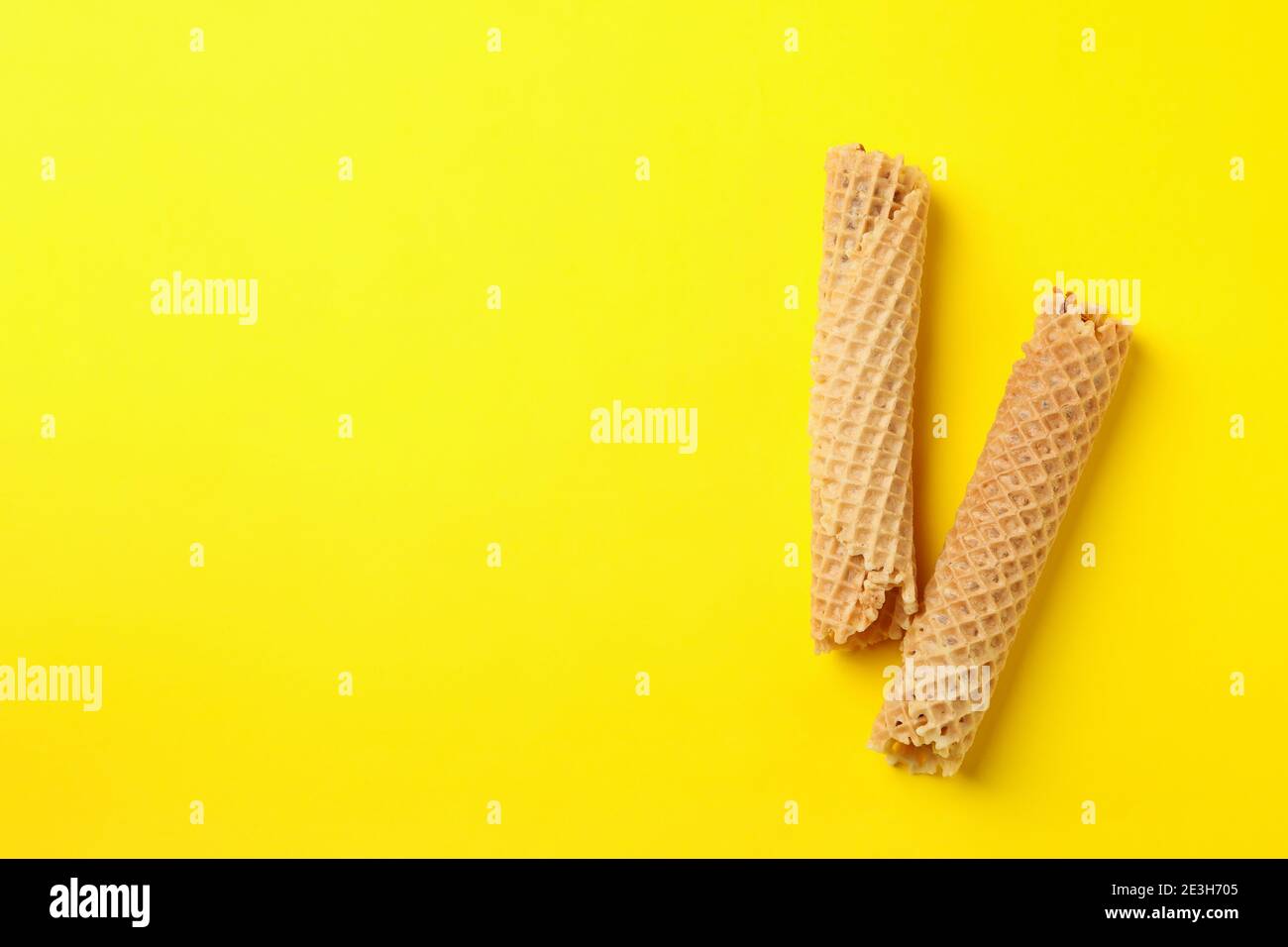 Tasty wafer rolls with condensed milk on yellow background Stock Photo