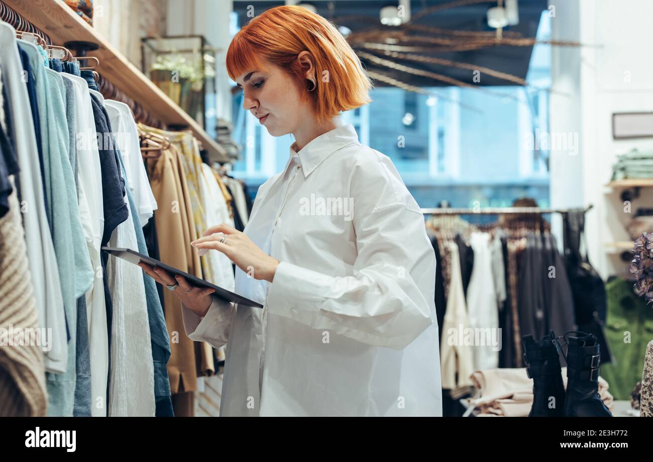Young woman in a store using a digital tablet. Fashion store owner using tablet computer. Stock Photo