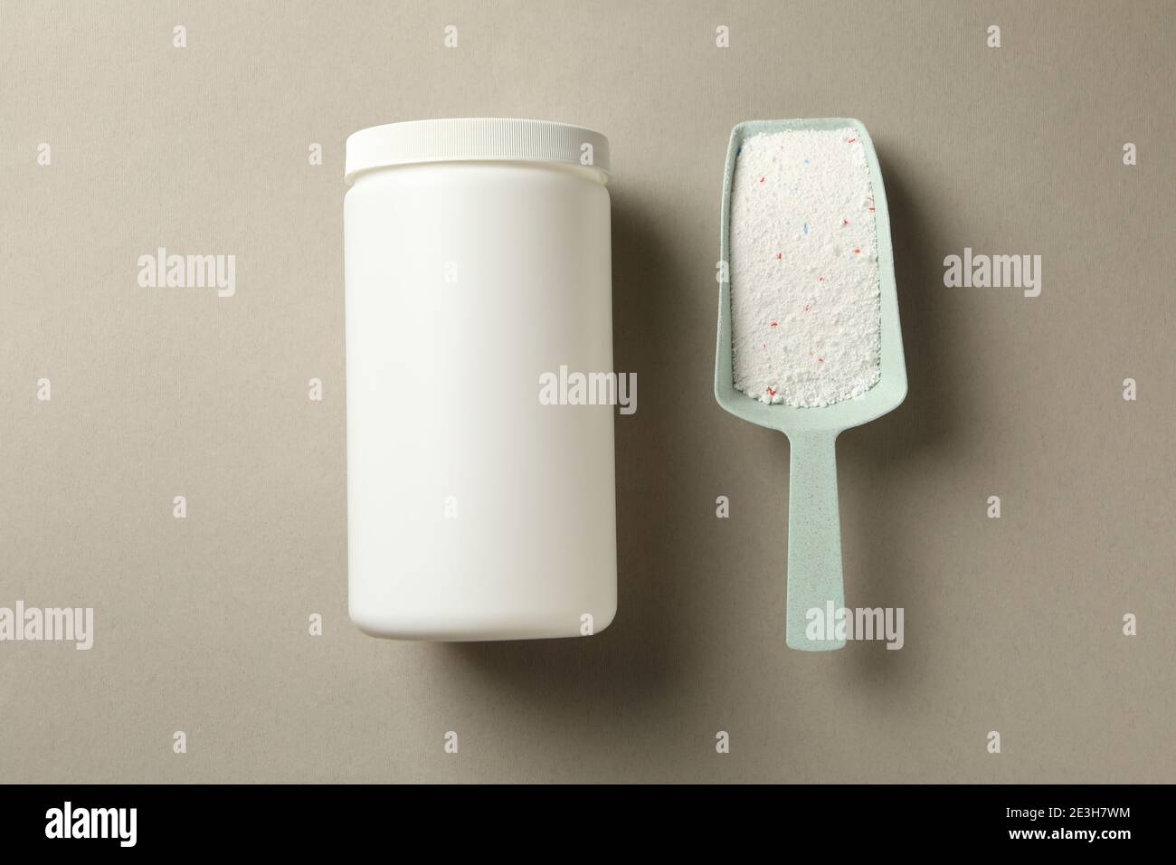 Plastic bottle and scoop with washing powder on gray background Stock