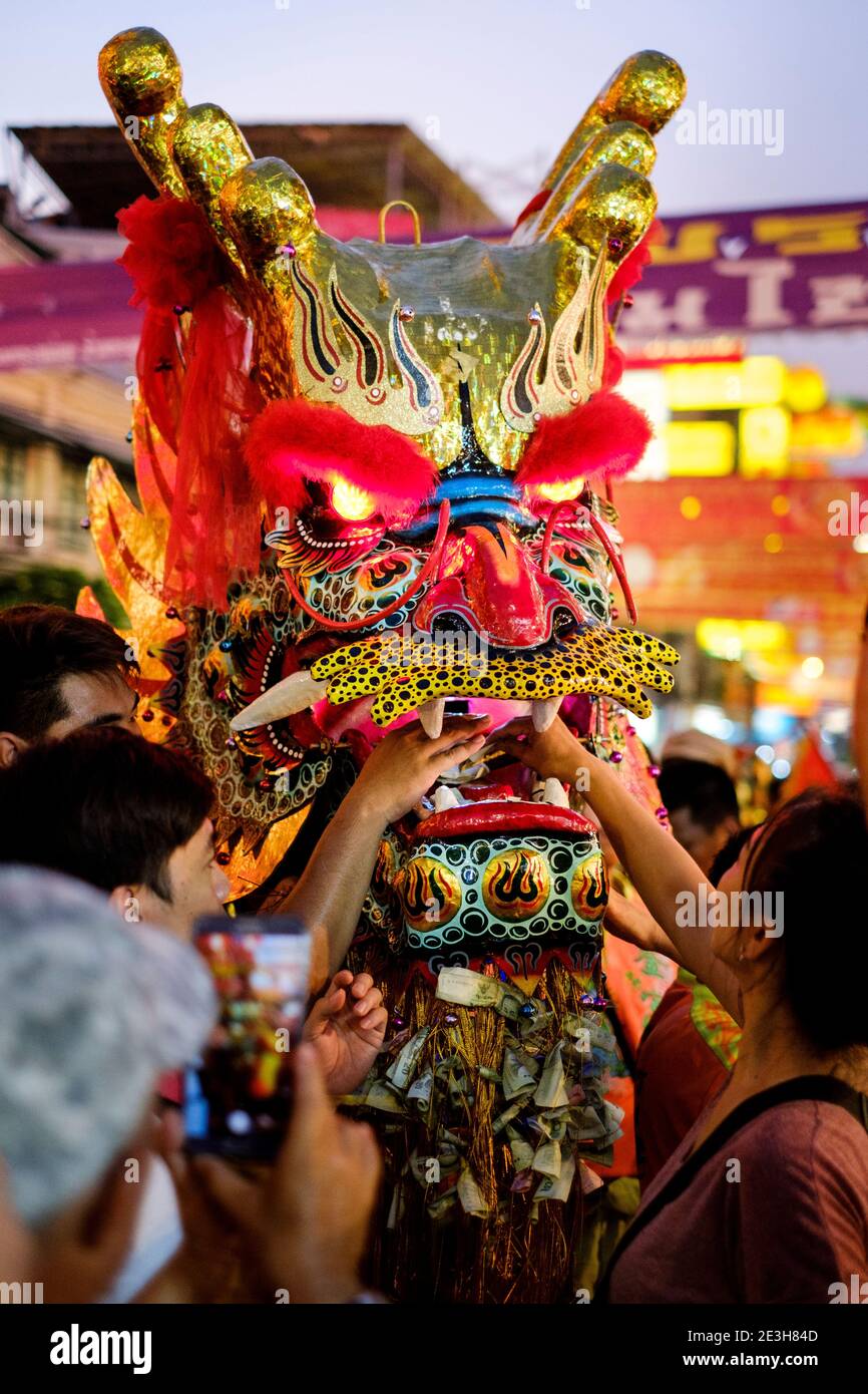 People leave offerings inside the mouth of a dragon figure used for a traditional dance during Lunar New Year in Yaowarat, Bangkok, Thailand. Stock Photo