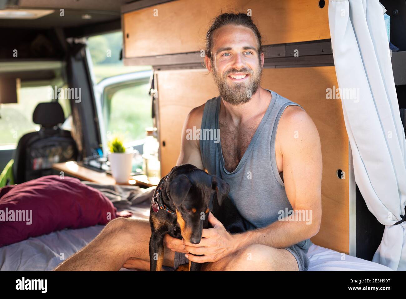 Smiling man and his dog inside a camper van Stock Photo