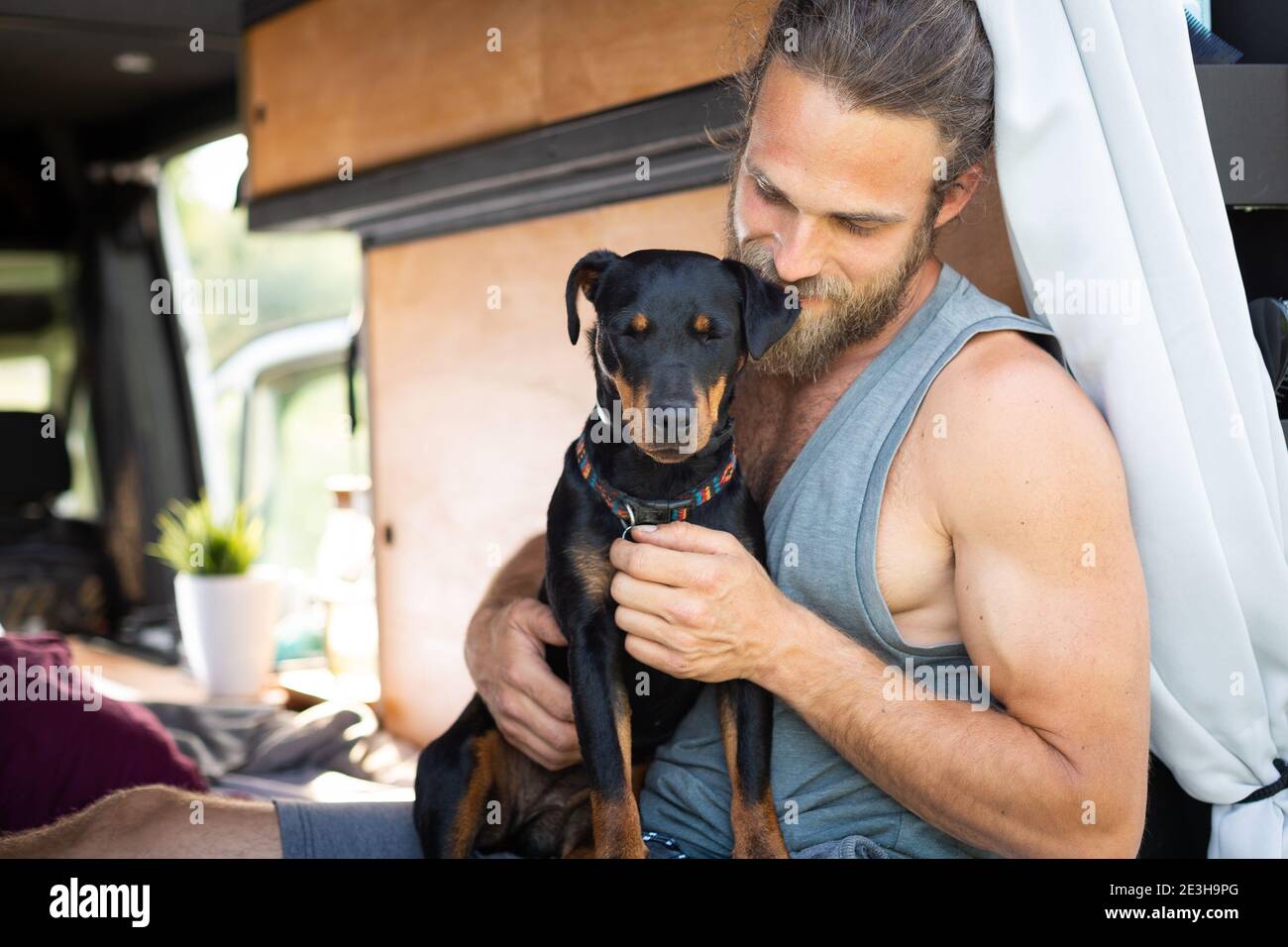 Man and his dog sitting in a camper van Stock Photo