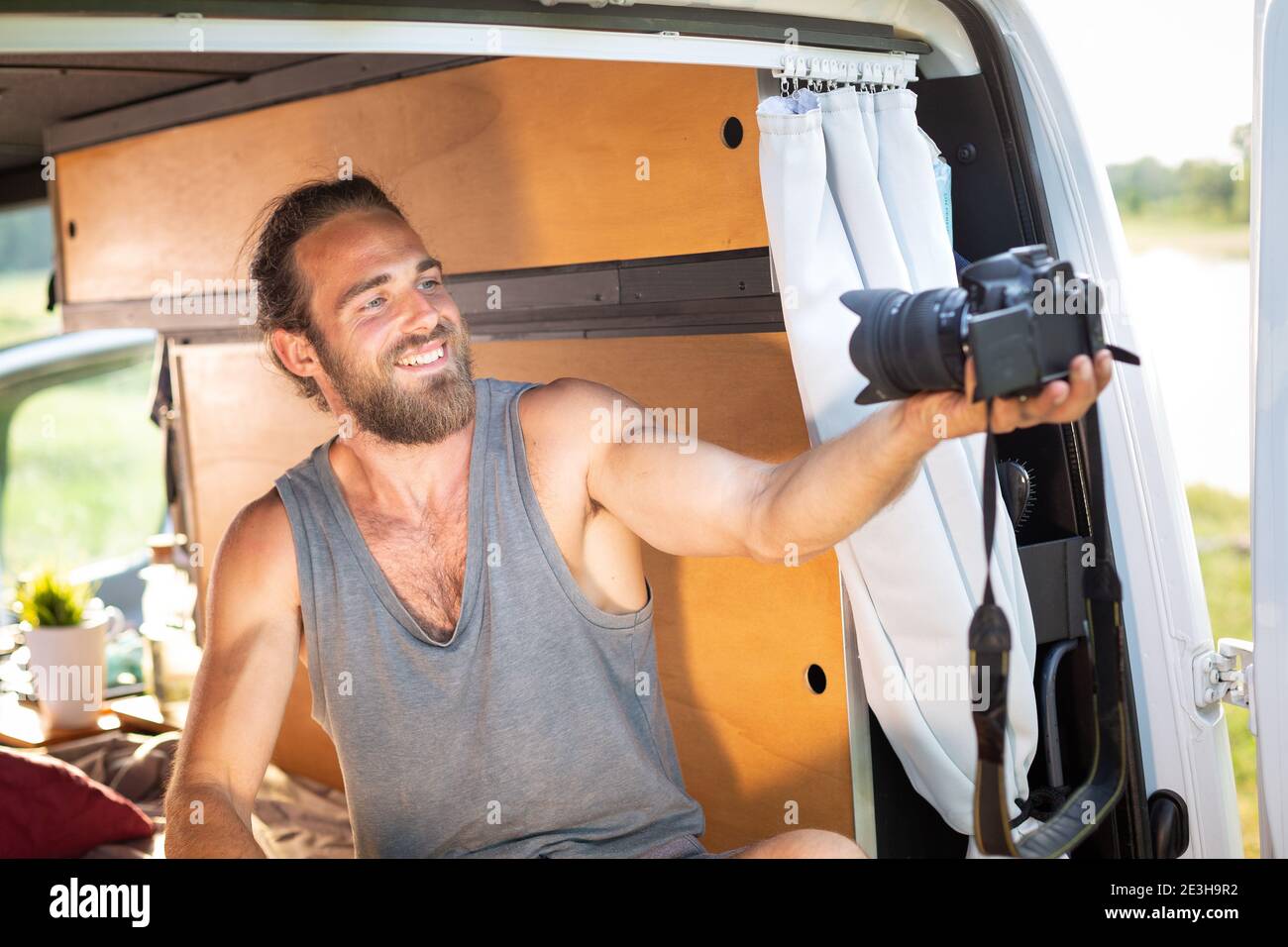 Smiling man in a camper van pointing a camera at himself Stock Photo