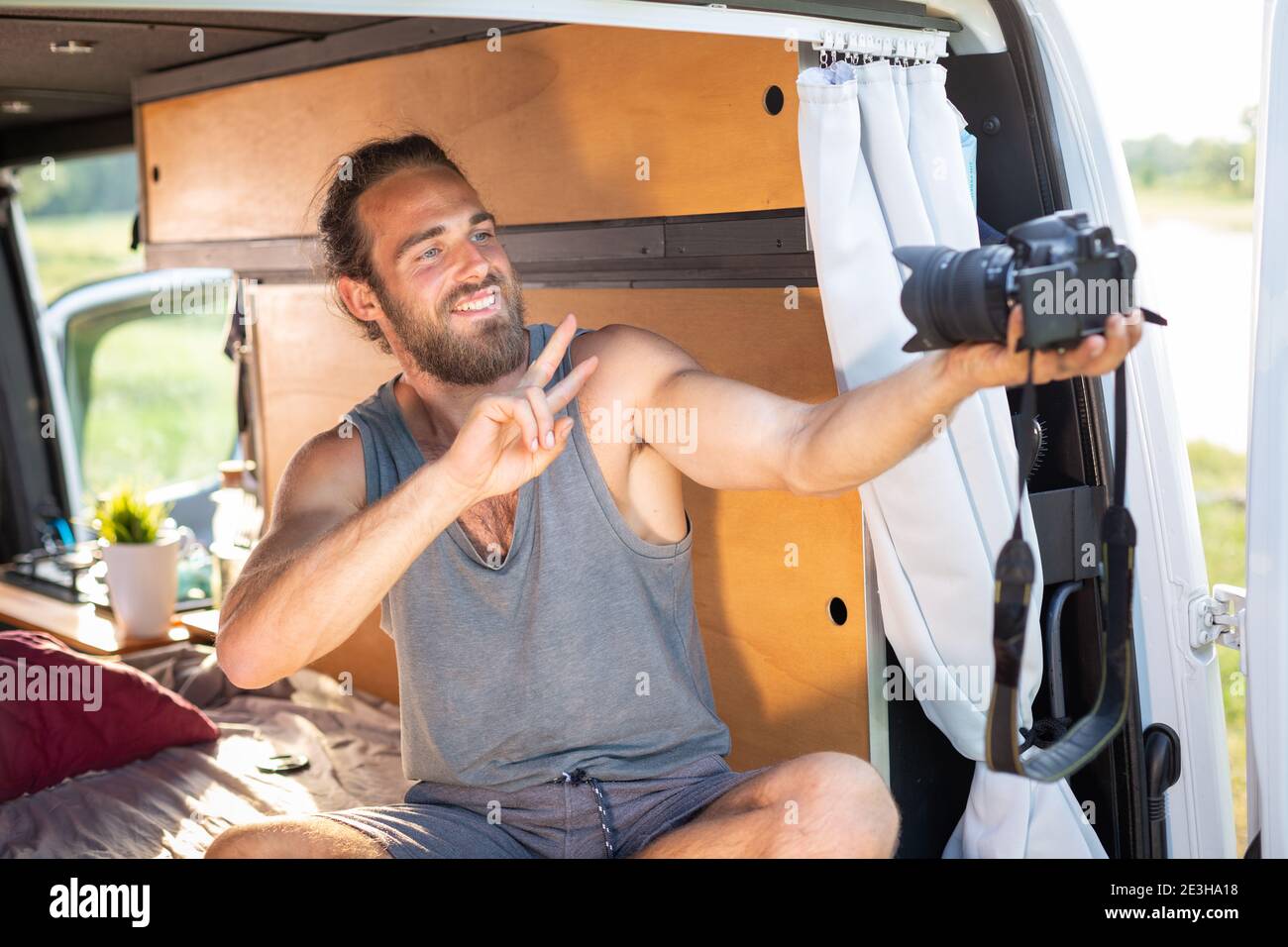 Young man in a camper van pointing a camera at himself Stock Photo