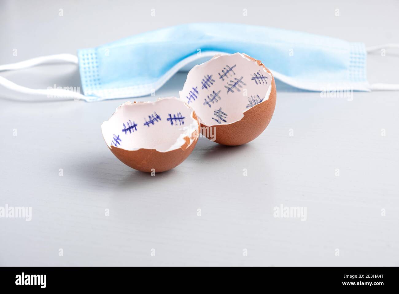 Hatched and opened egg with calendar markings and a medical mask in the background with corona virus meaning Stock Photo