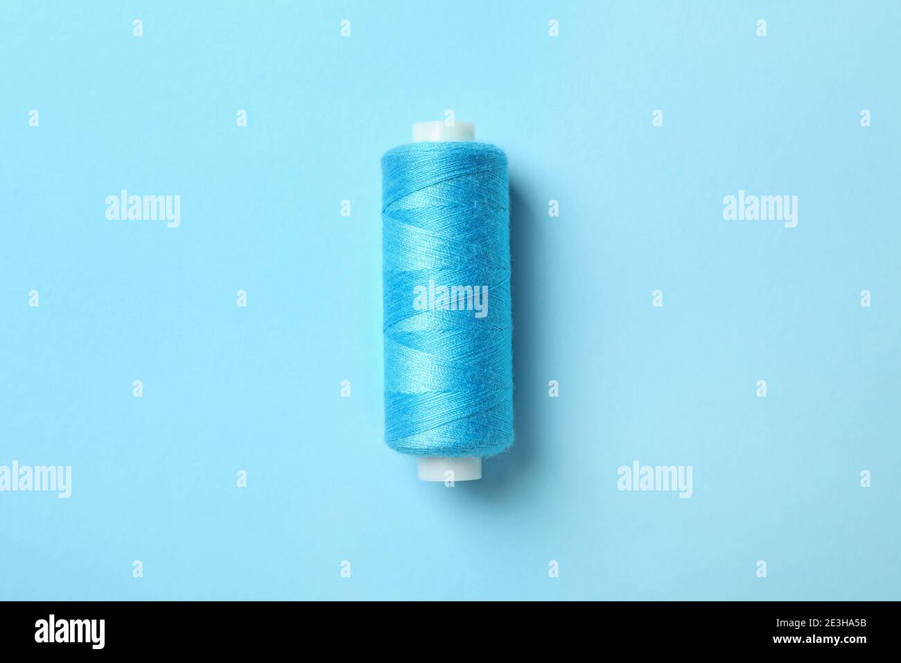 Blue sewing thread on blue background, space for text Stock Photo - Alamy