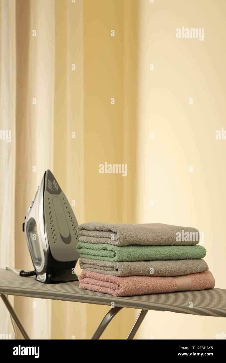 Ironing board with iron and pile of towels Stock Photo Alamy