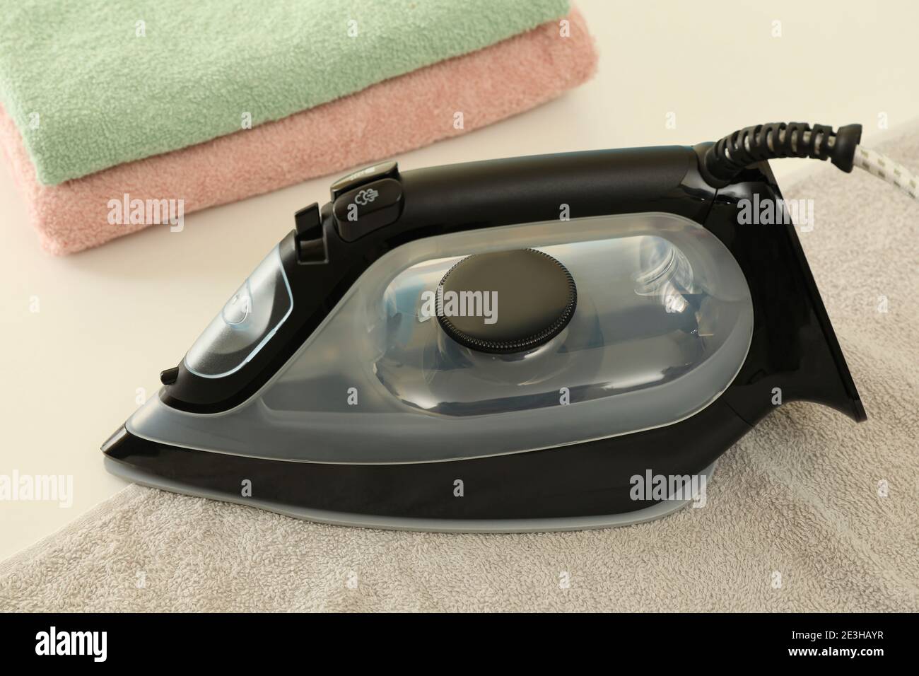 Modern iron and towels on white table, close up Stock Photo