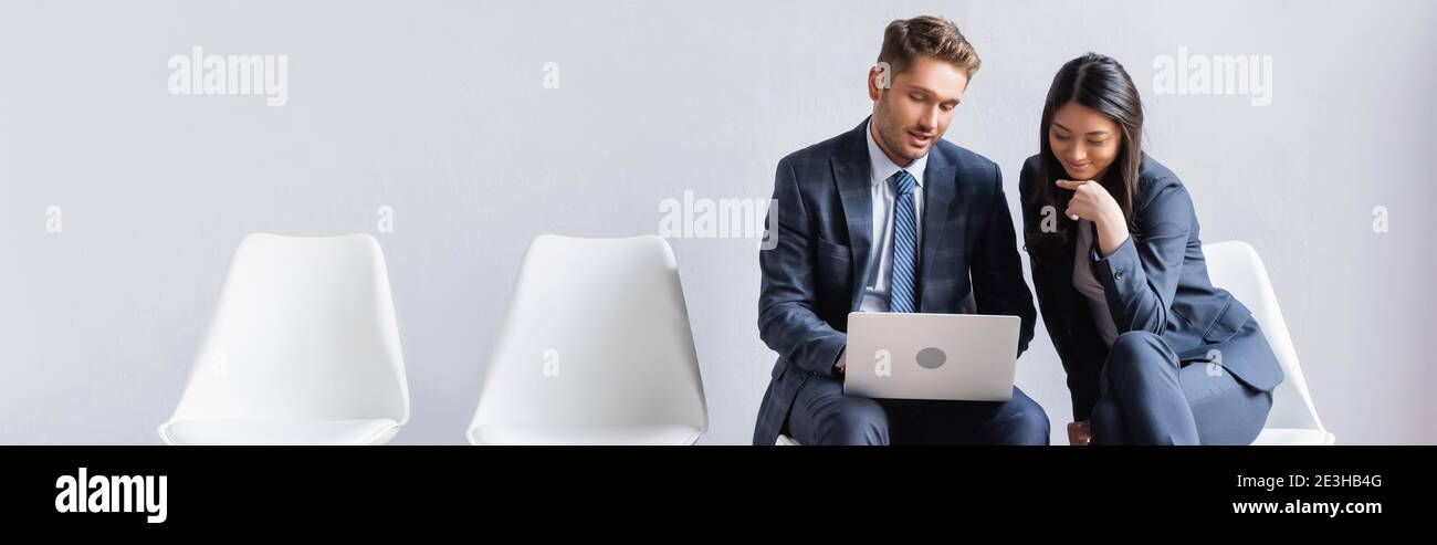 Smiling multiethnic businesspeople using laptop in hall, banner Stock Photo