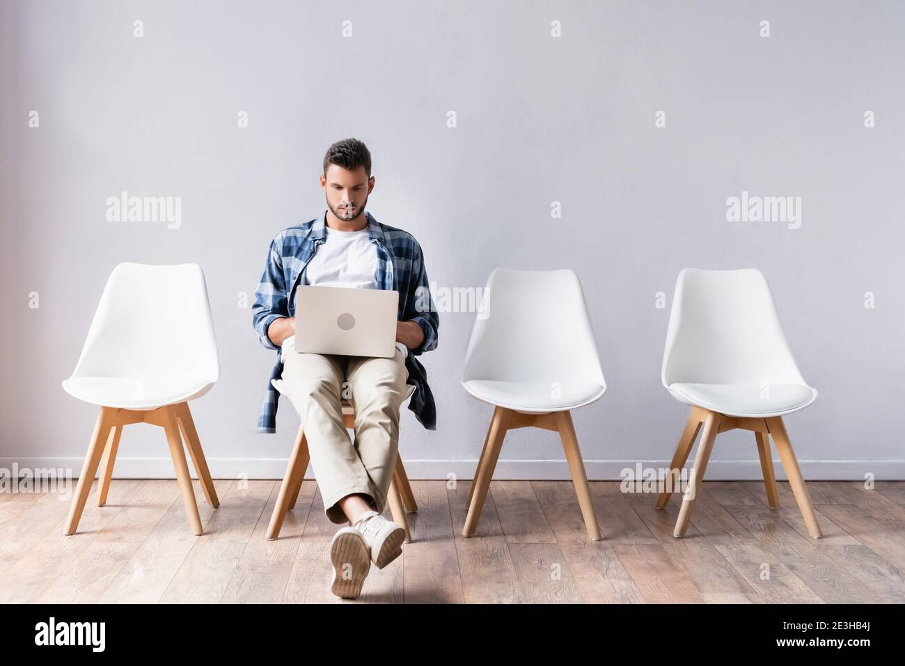 Freelancer in casual clothes using laptop in hall Stock Photo