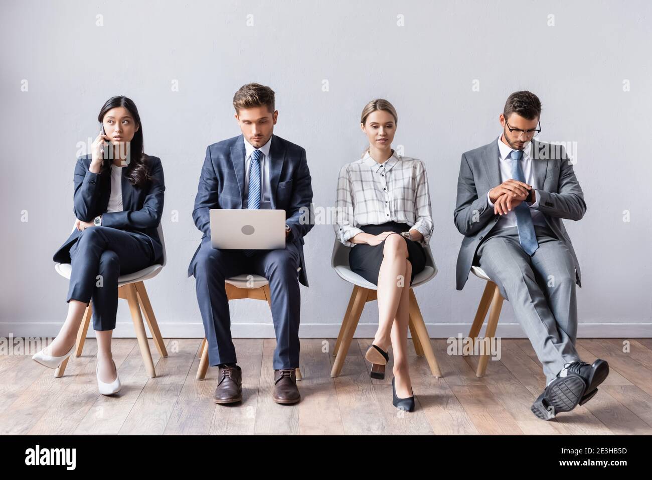 Multiethnic business people with laptop and smartphone waiting in hall Stock Photo
