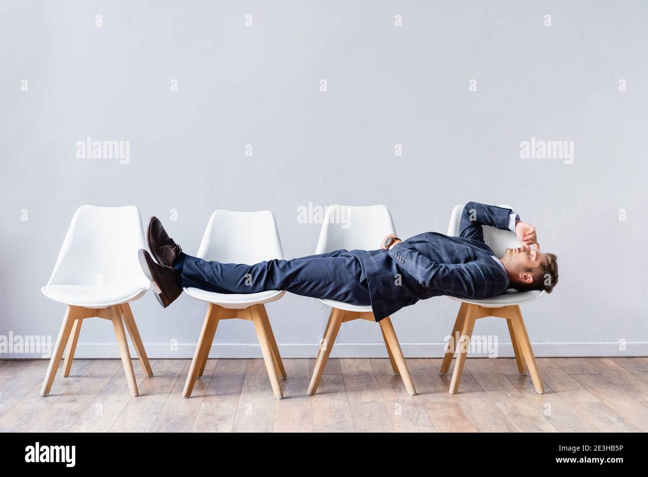 Businessman in suit lying on chairs while waiting job interview Stock Photo