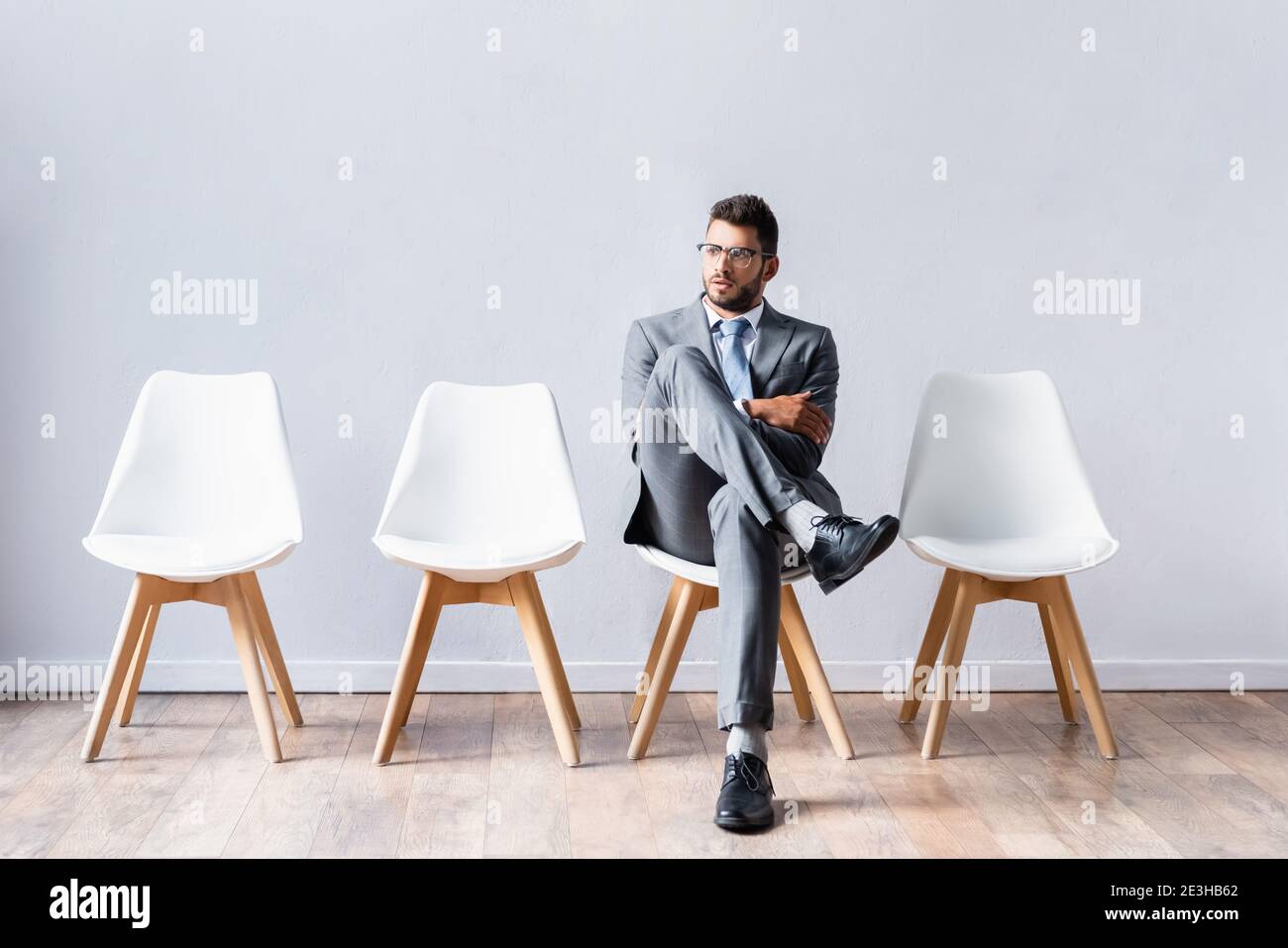 Young businessman sitting with crossed legs on chair in office Stock Photo