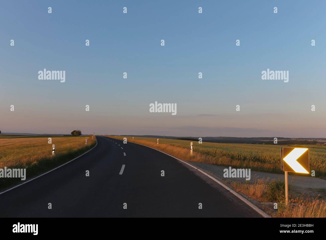 Amazing asphalt curved road with fields and traffic sign view in ...
