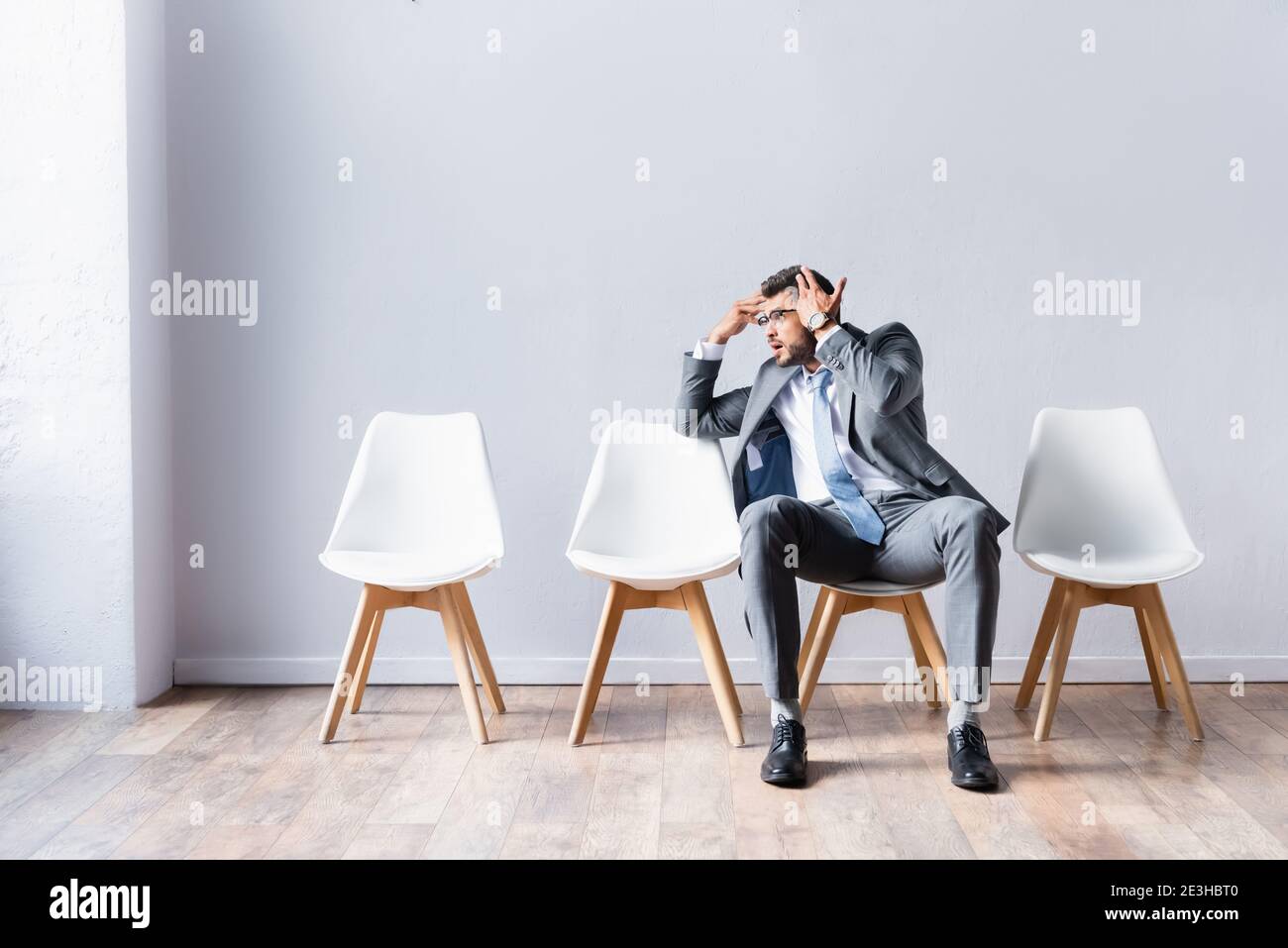 Tired businessman pointing at head while waiting job interview in office Stock Photo