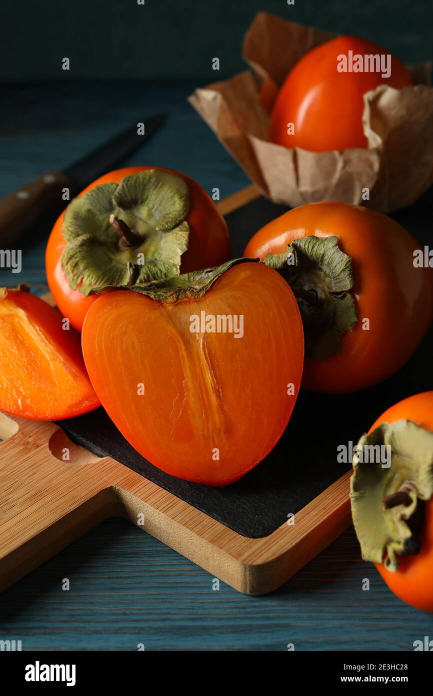 Board with ripe persimmon and knife on wooden background Stock Photo