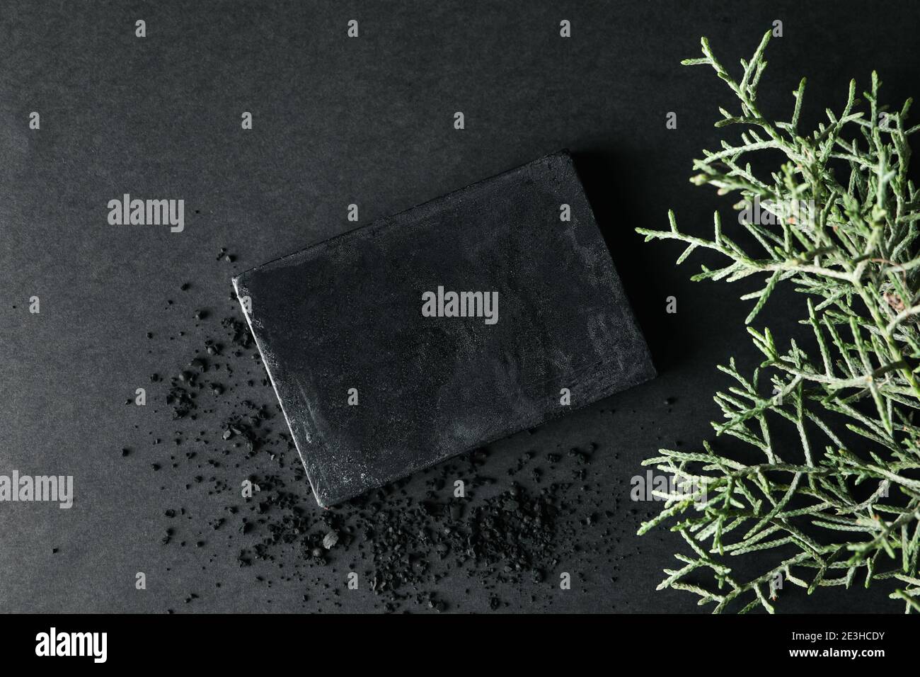 Charcoal soap and thuja branches on black background Stock Photo