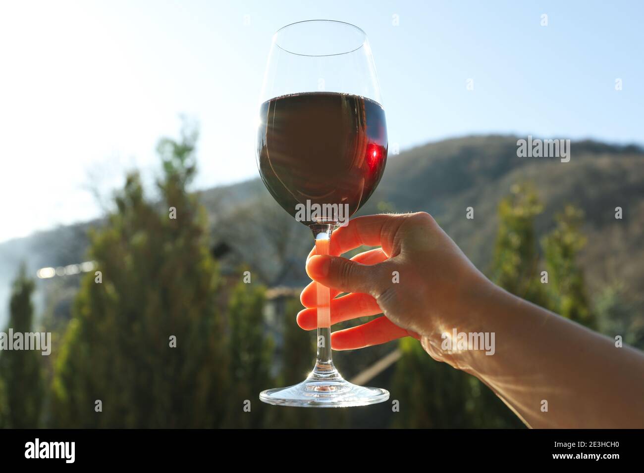 Female hand holding glass of red wine against mountain background Stock ...