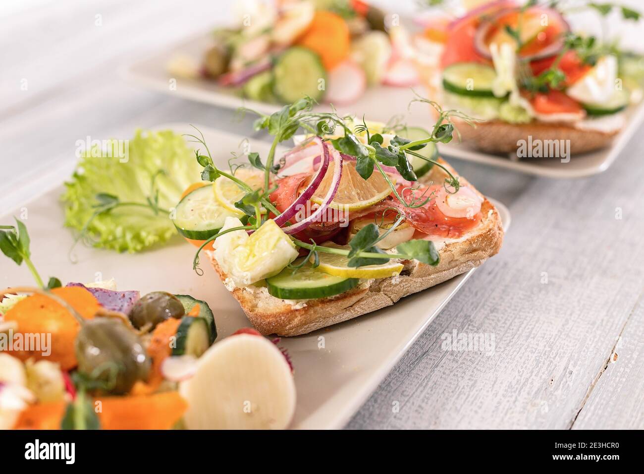 Quick and healthy food recipes. Salad with salmon, vegetables and herbs on Italian ciabatta bread. Mediterranean dish recipes. Selective focus. Stock Photo