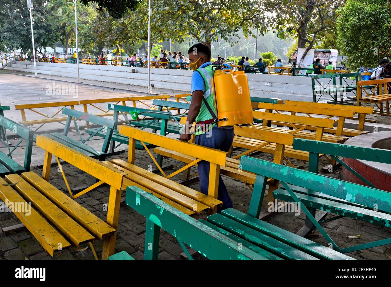 A covid frontline worker disinfecting the benches at a polling booth in Bihar. Stock Photo