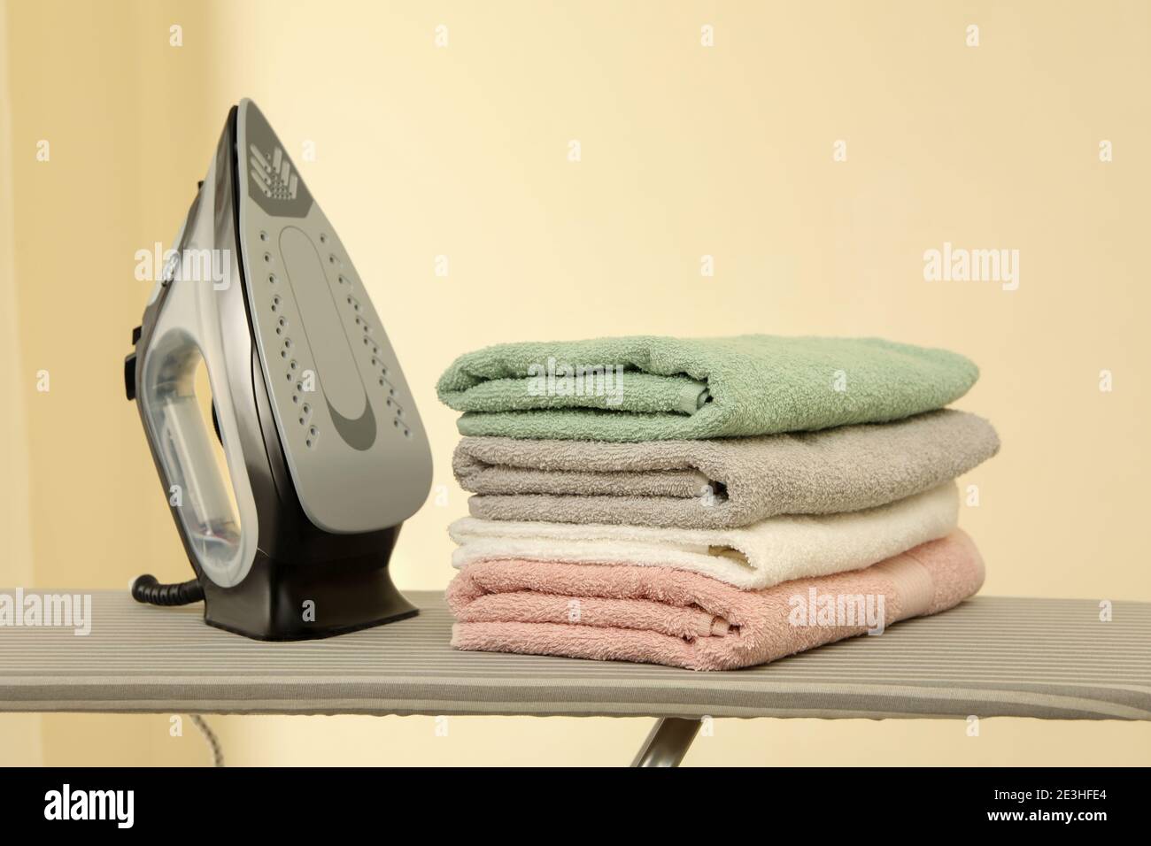 Ironing board with iron and pile of towels Stock Photo Alamy