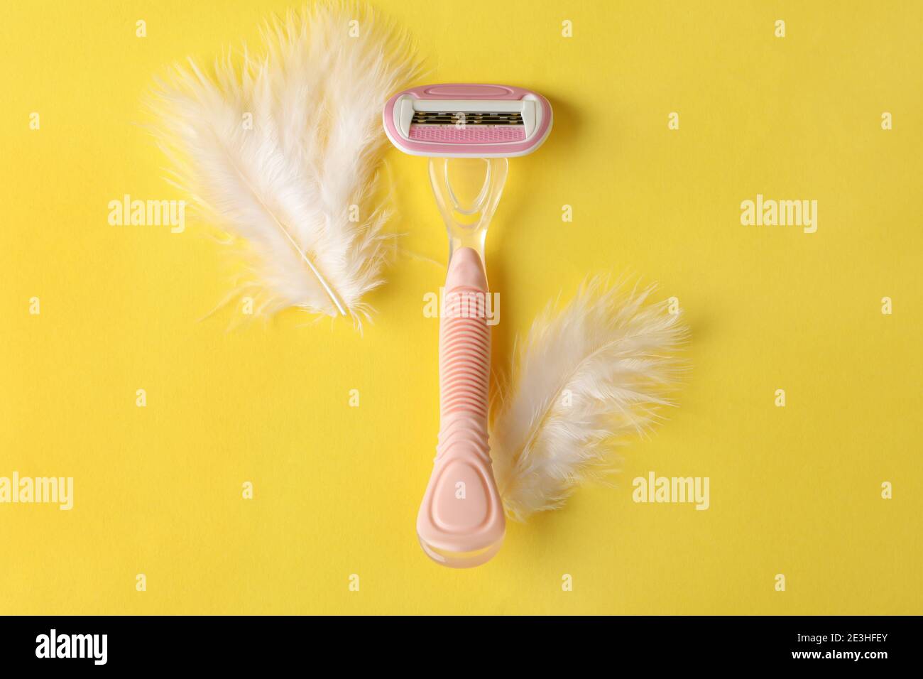 Razor and feathers on yellow background, place for text Stock Photo