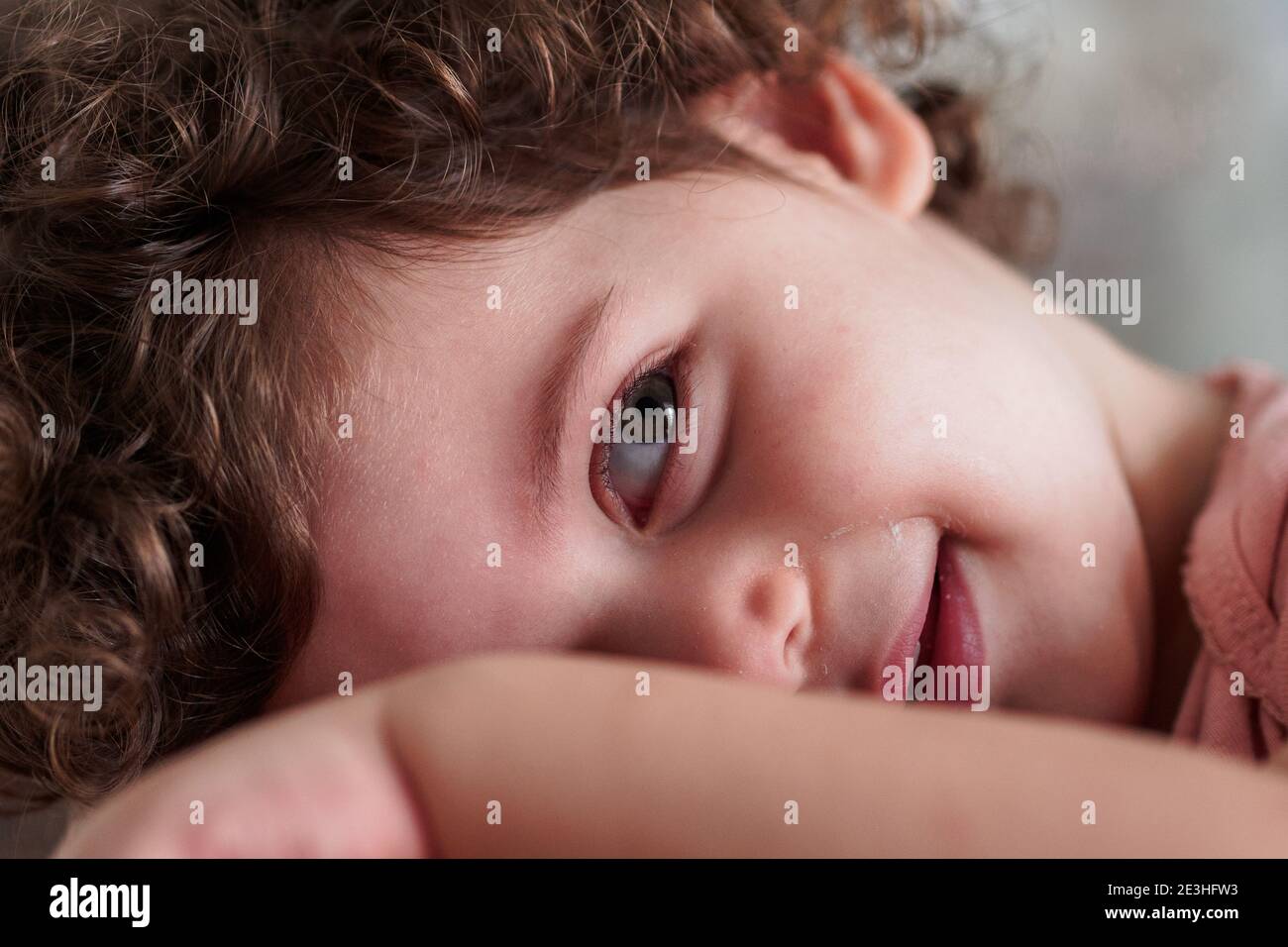 Bashful toddler hides her face behind her hand Stock Photo