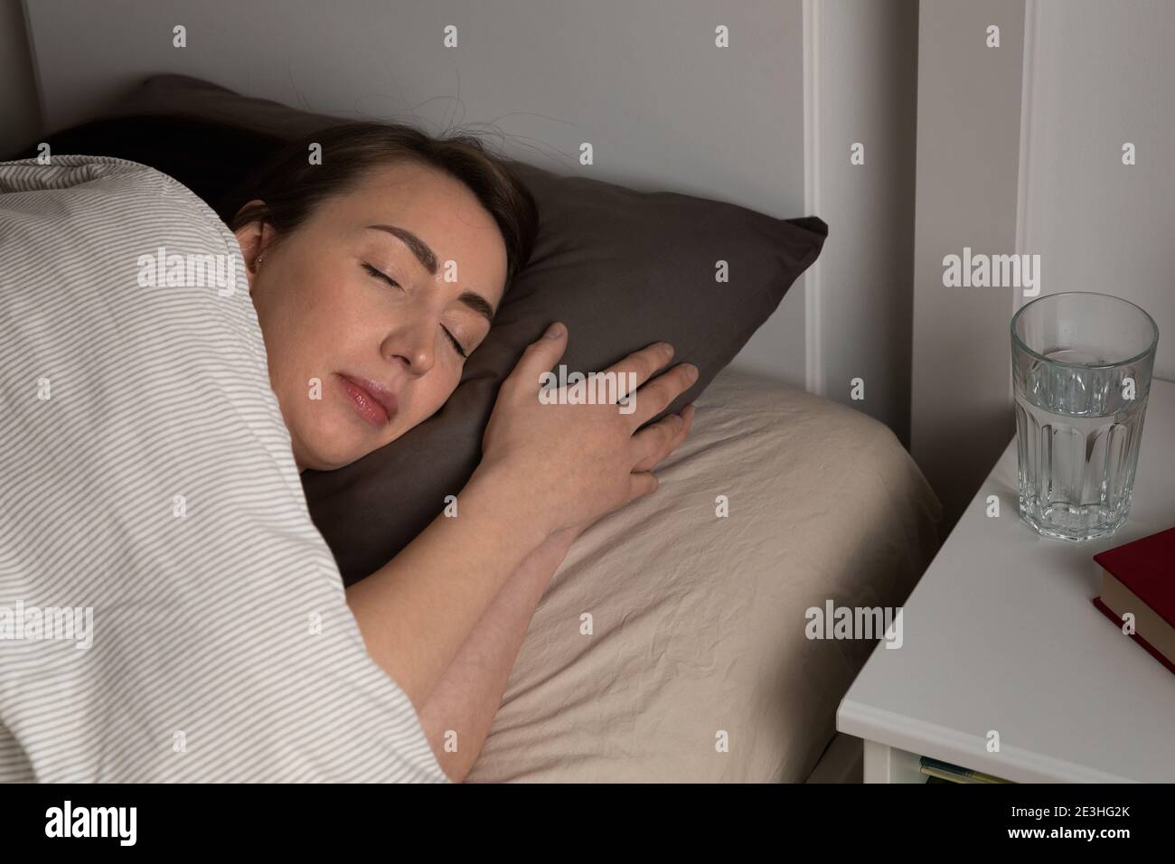 Young women sleeping in bed at night with a peaceful smile. Happy dreams and good sleep. Stock Photo