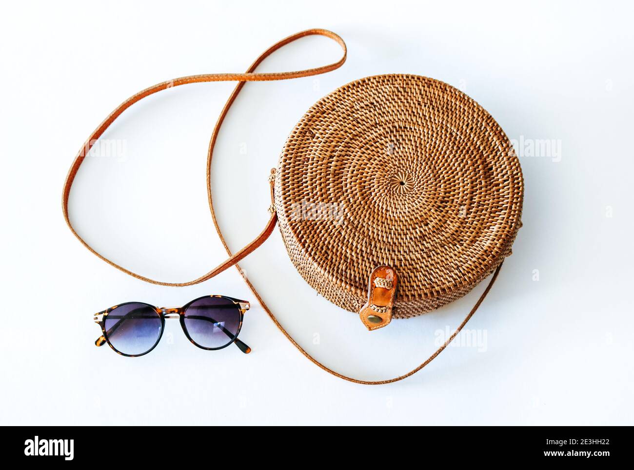 Boho style, round Ata Rattan Bag with a leather shoulder strap and sunglasses, isolated on white background Stock Photo