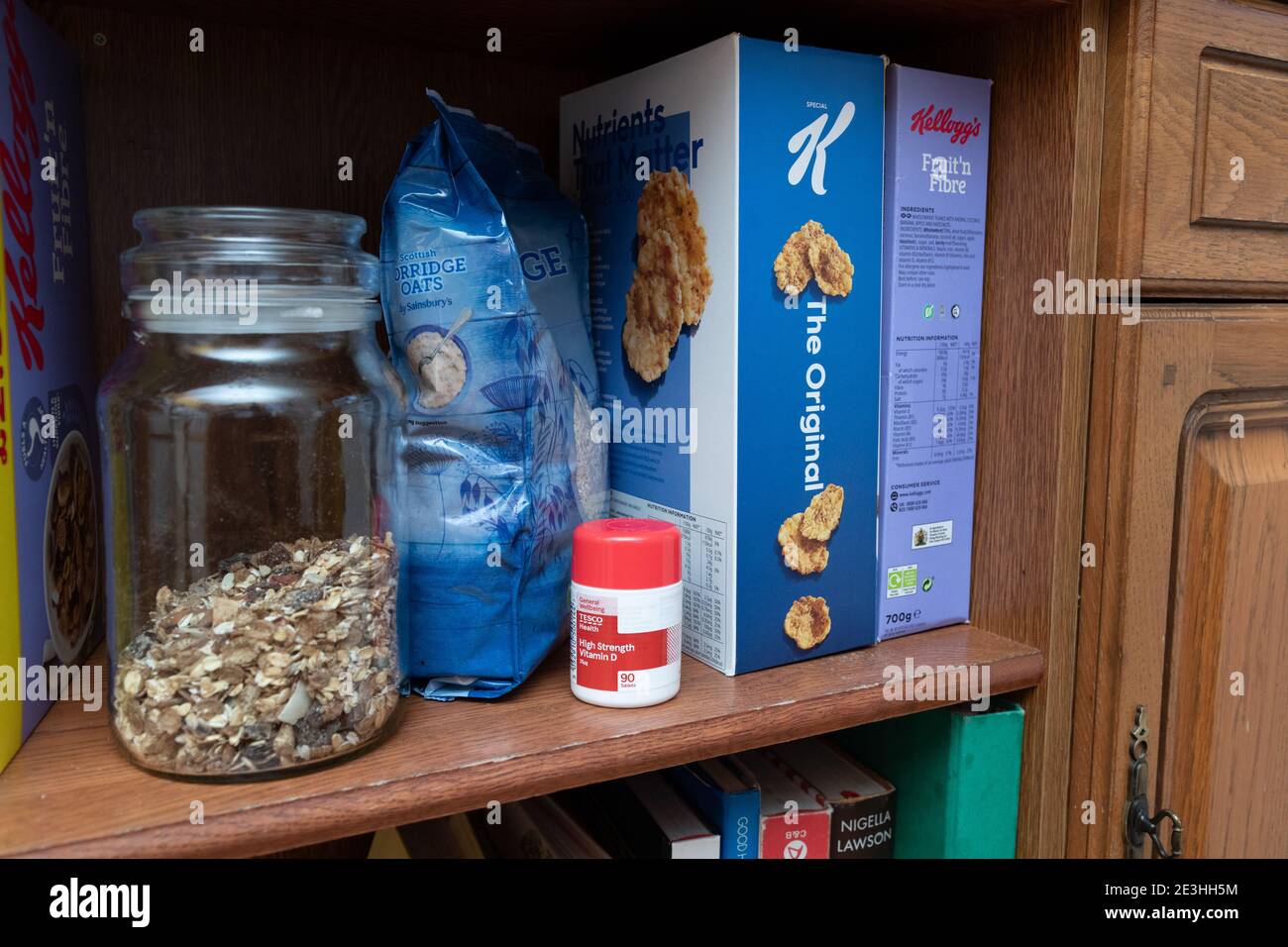 A row of breakfast cereals plus a bottle of Vitamin D pills on a shelf