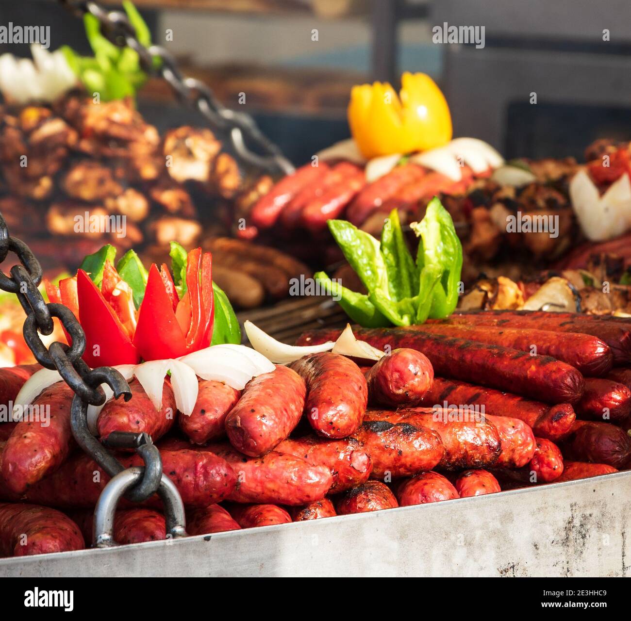 Grilled sausages and kebabs assortment on big round grill at street food market stall in Paris. Selective focus. Stock Photo