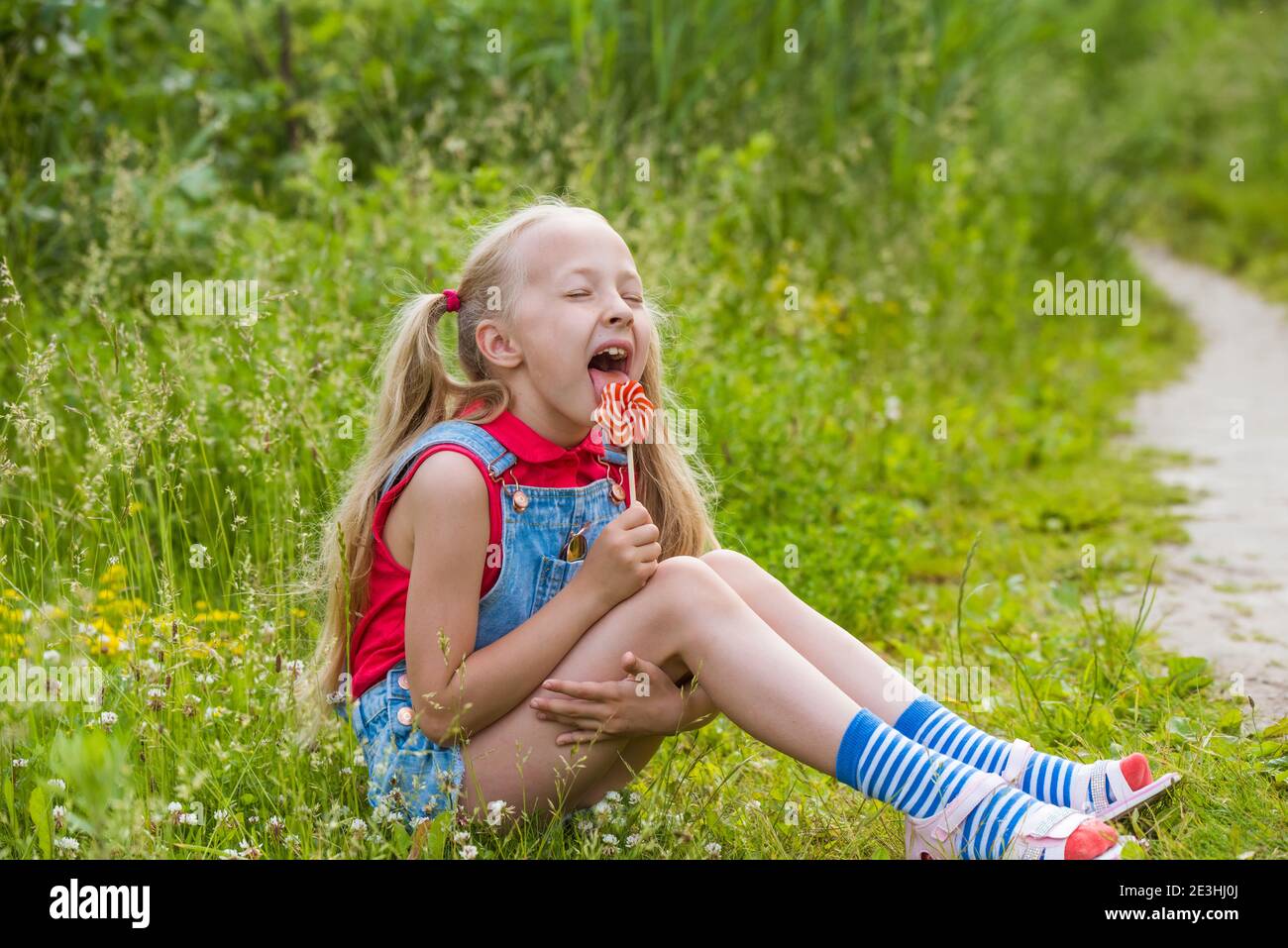 Blonde little girl with long hair and candy on a stick Stock Photo