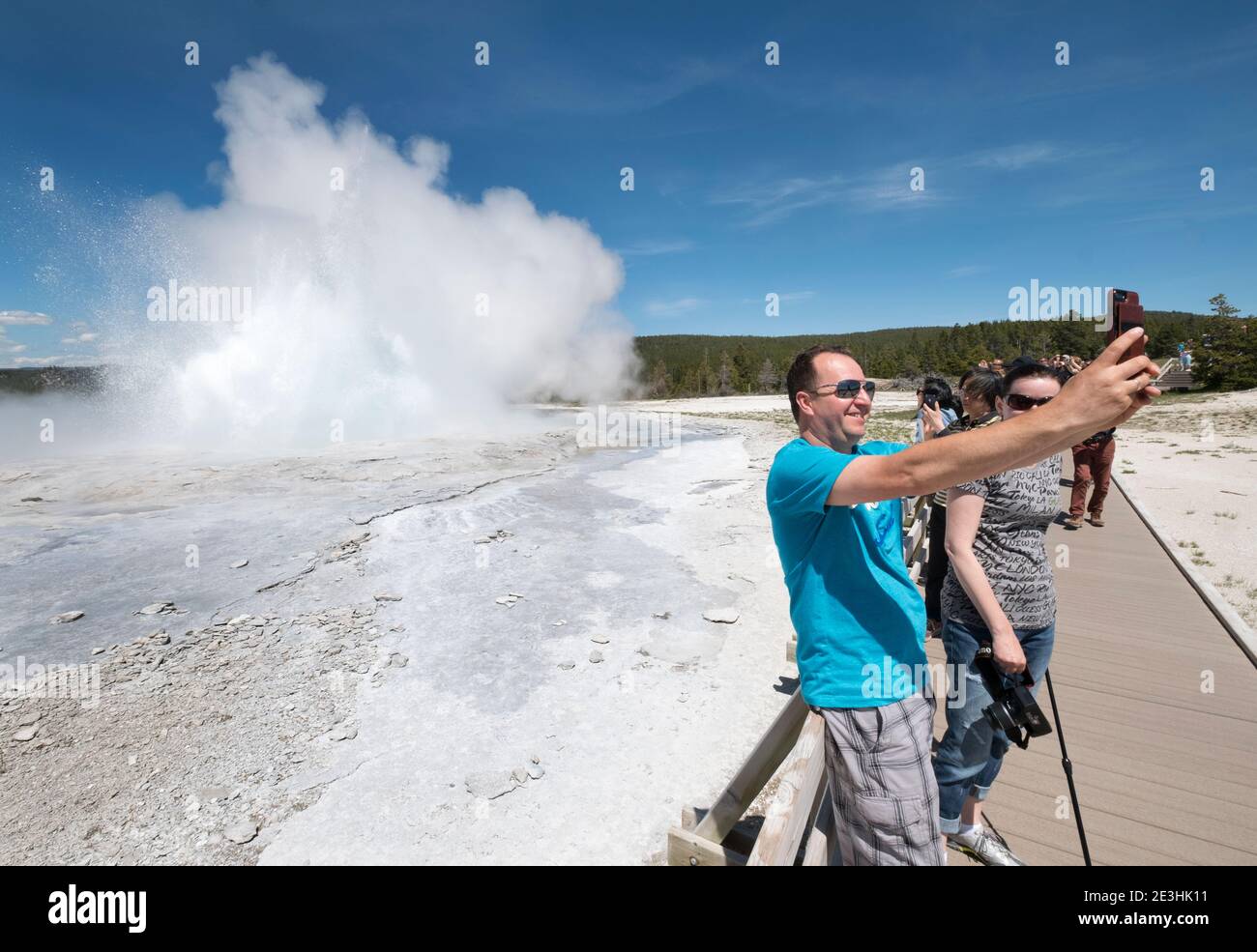 Tourists take pictures of Clepsydra Geyer erupting, Yellowstone, National Park, Wyoming USA Stock Photo