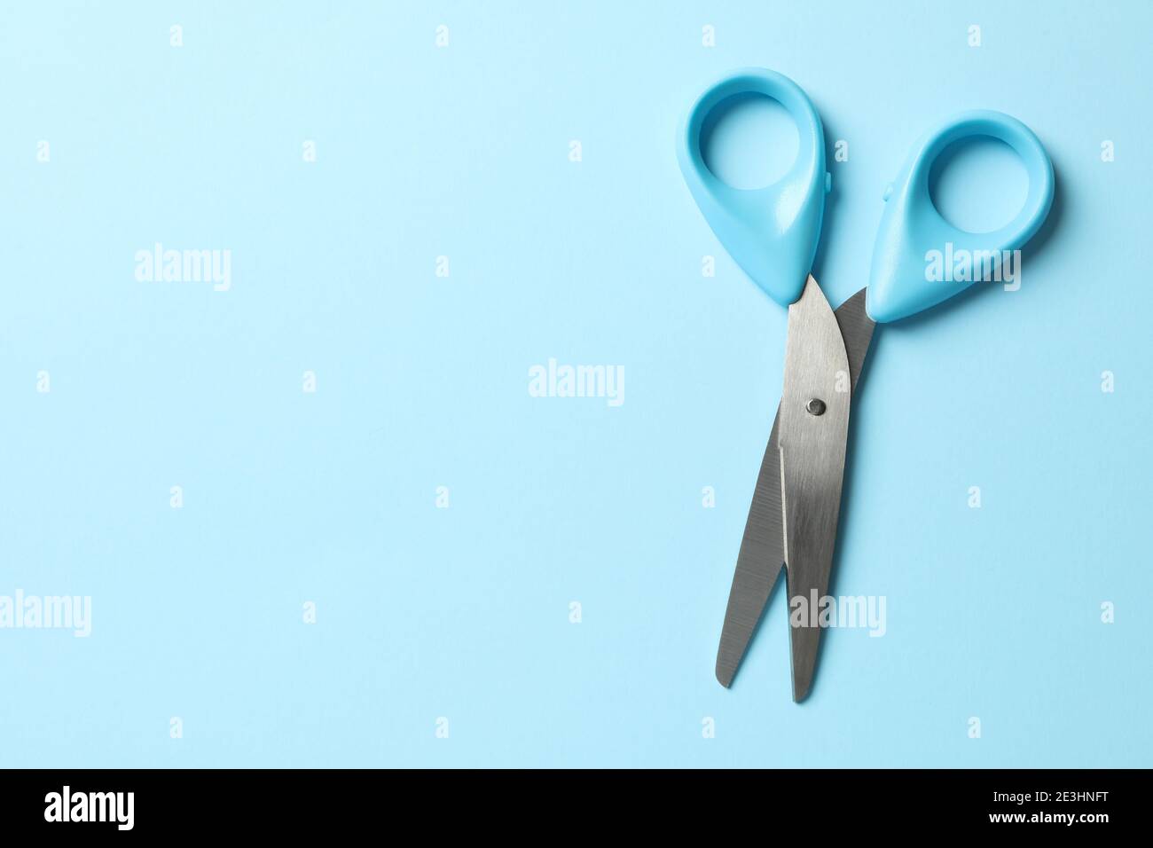Blue scissors on blue background, space for text Stock Photo