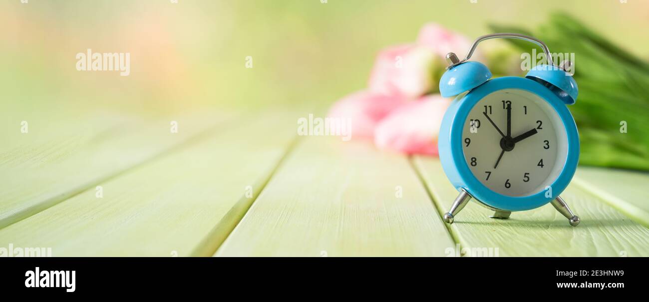Spring time daylight saving concept - with alarm clock and flowers Stock Photo
