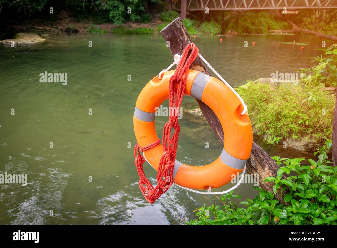 A rubber ring with a rope hanging on a wooden pole along the river was prepared for rescue. Stock Photo