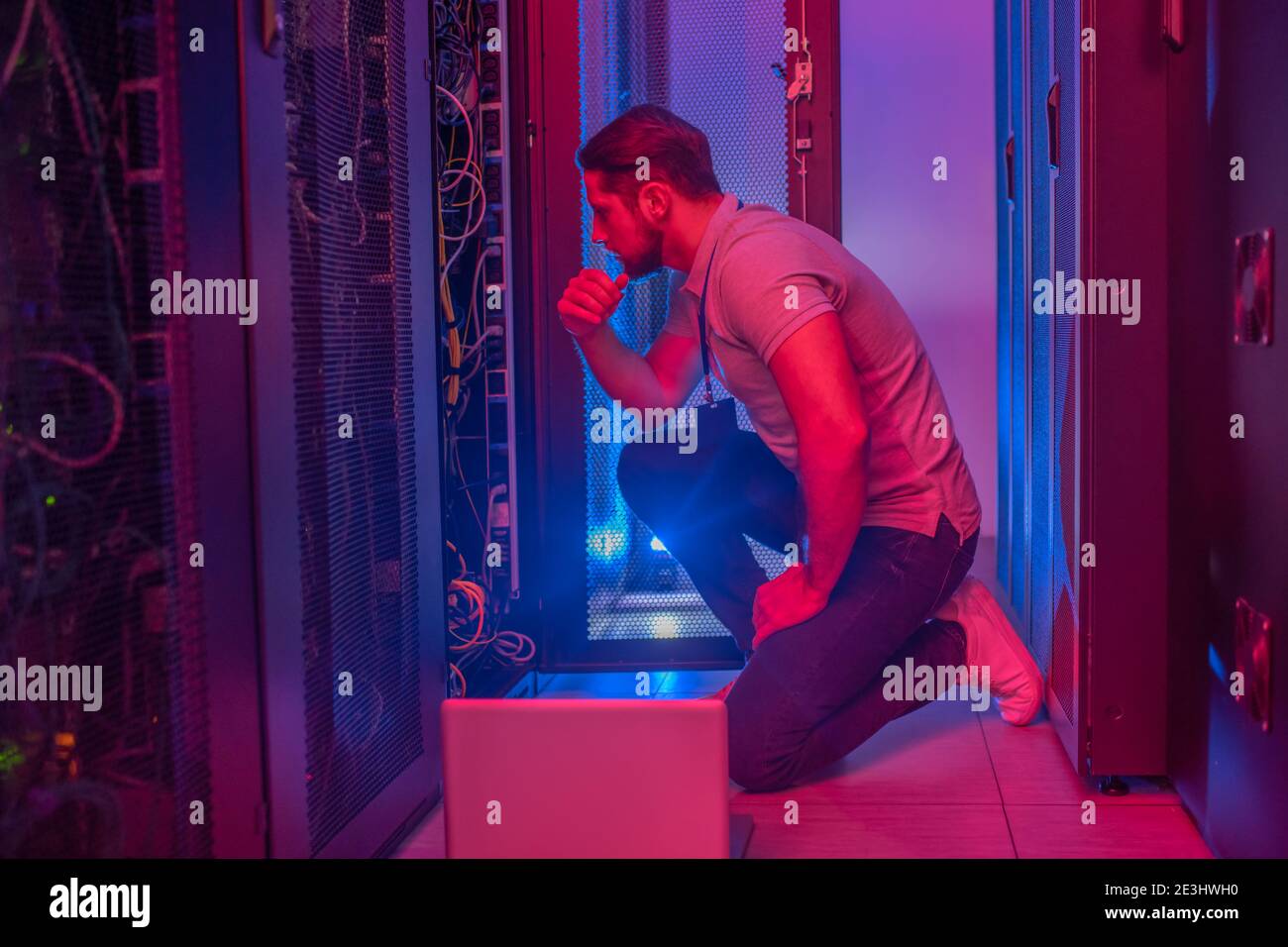 Thinking man crouched near open servir rack Stock Photo