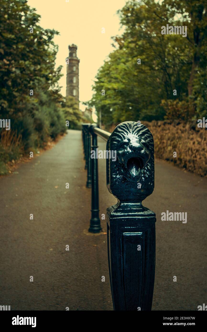 Lion head on hand railings leading to Nelson monument on Calton Hill in Edinburgh with green trees on both sides. Stock Photo