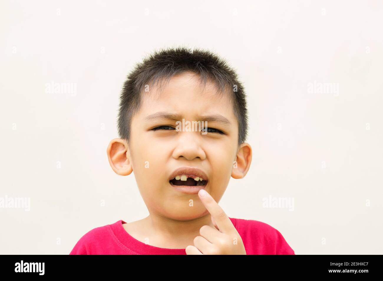 The boy is holding his hand on his cheek and red face with pain from