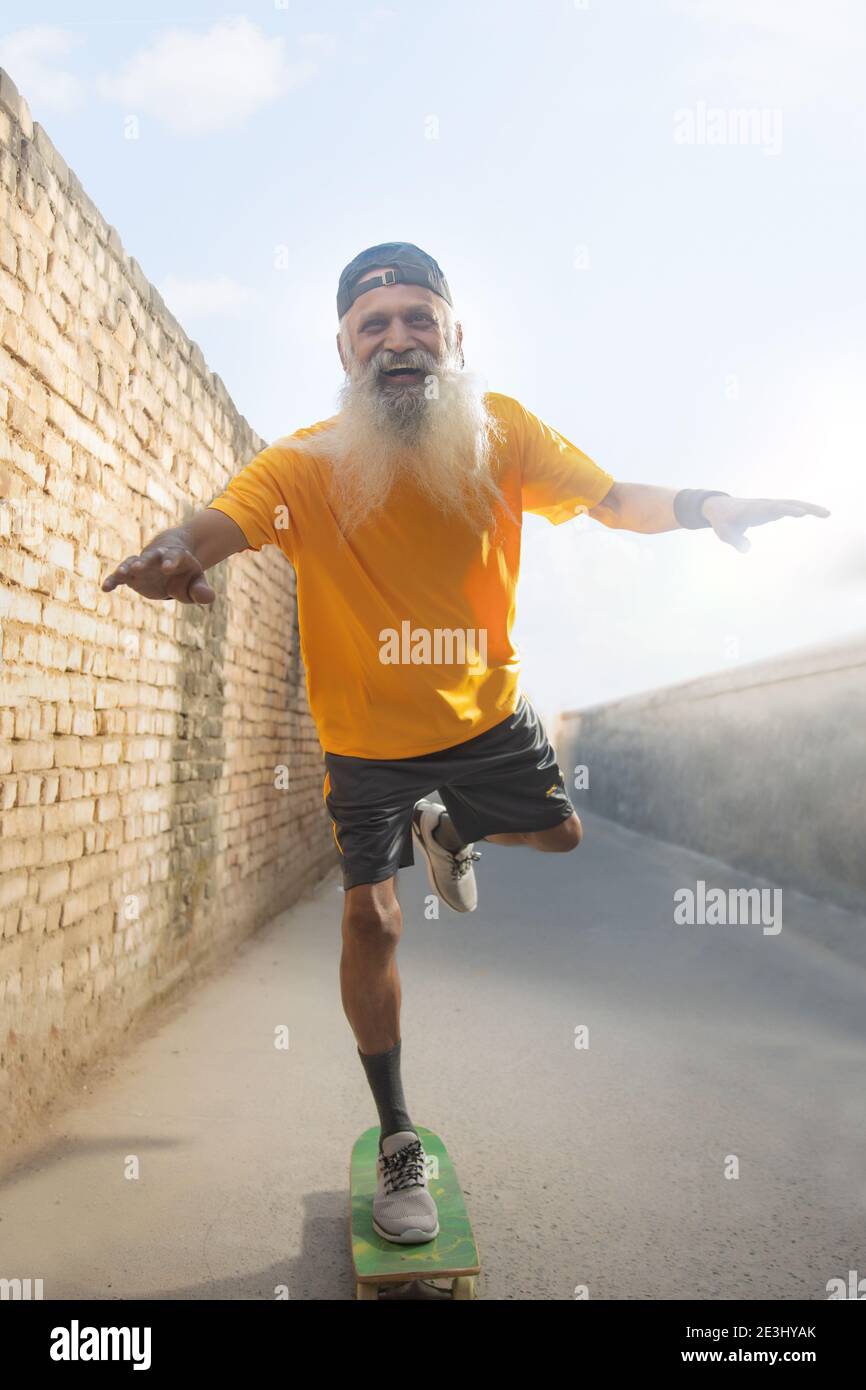 A BEARDED OLD MAN CHEERFULLY POSING WHILE CYCLING Stock Photo