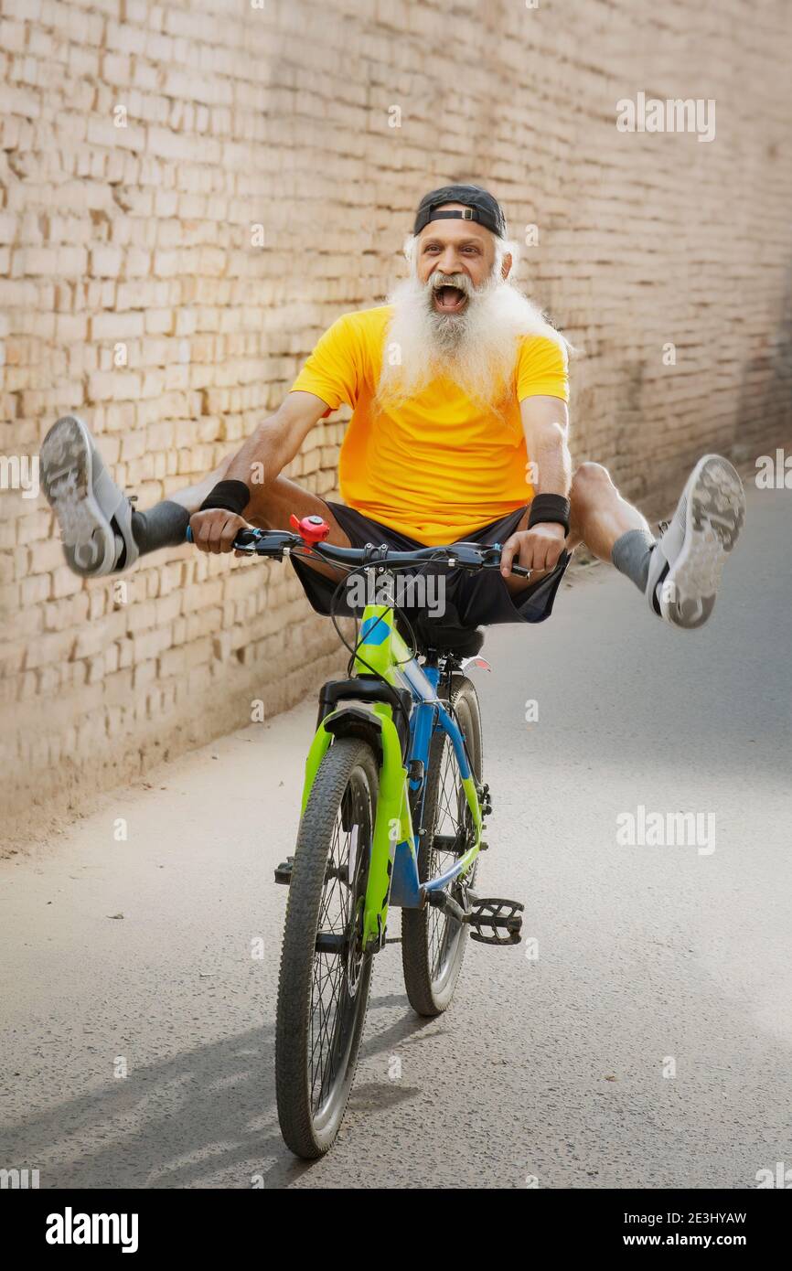A BEARDED OLD MAN ENTHUSIASTICALLY USING SKATE BOARD Stock Photo
