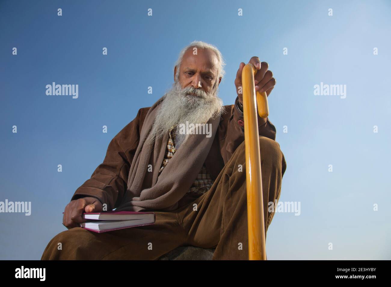 AN OLD MAN WITH LONG BEARD SITTING WITH BOOK AND THINKING Stock Photo