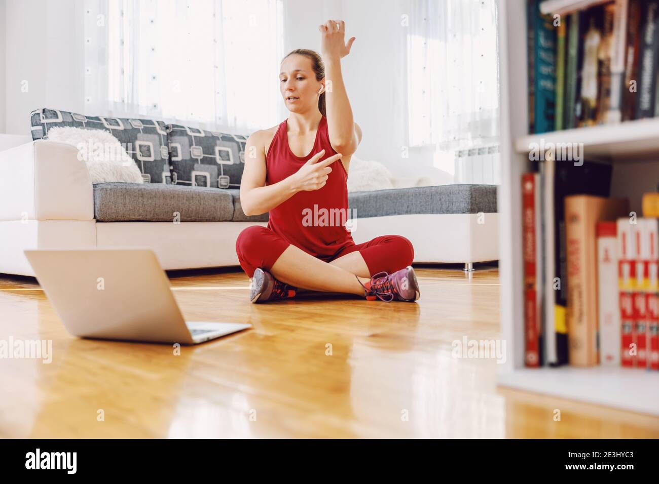 Fitness instructor sitting on the floor at home and explaining ...