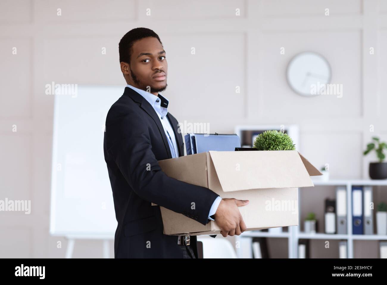 Young black man got fired, holding box with his belongings Stock Photo