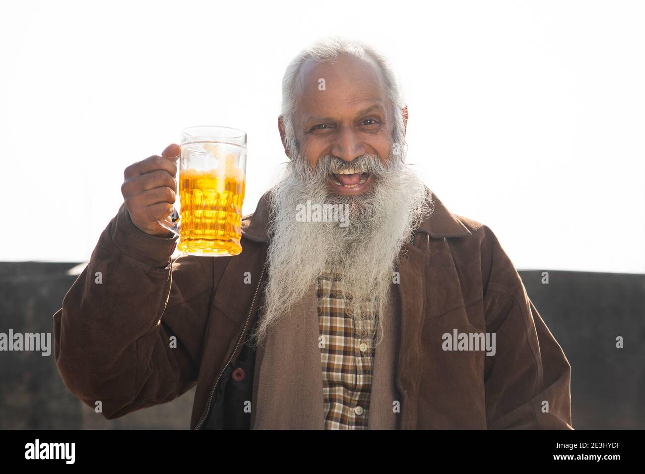 A CHEERFUL OLD MAN HAPPILY HOLDING GLASS OF BEER Stock Photo