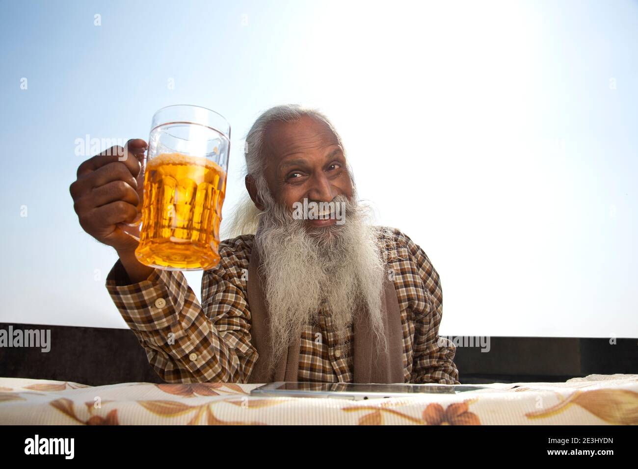 A BEARDED OLD MAN HAPPILY LOOKING AWAY WITH BEER IN HAND Stock Photo