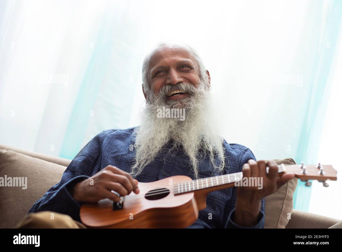 A HAPPY OLD MAN LOOKING ABOVE AND PLAYING UKULELE IN FREE TIME Stock Photo  - Alamy