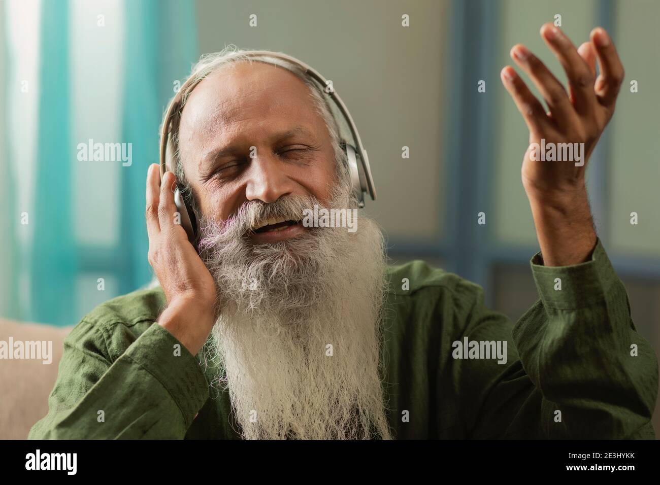 A HAPPY OLD MAN SINGING ALONG WHILE LISTENING TO MUSIC Stock Photo
