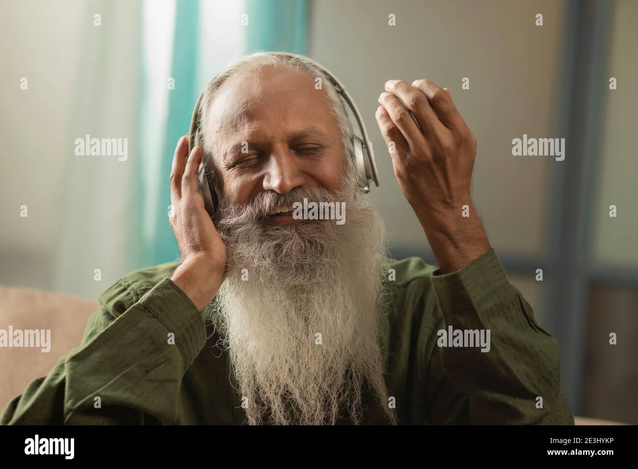 A HAPPY BEARDED MAN SINGING ALONG WHILE LISTENING TO MUSIC Stock Photo